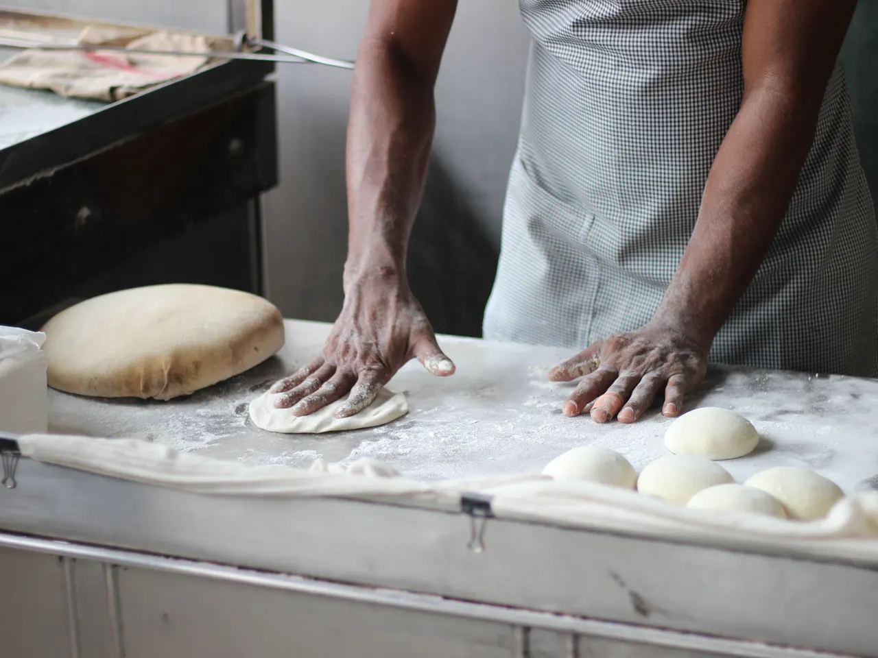 Mãos trabalhando a massa em uma bancada de produção de pão